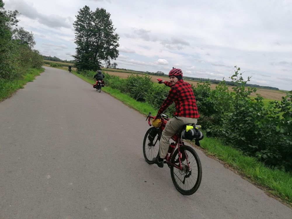 Rowerzyści na asfaltowej drodze wśród pól